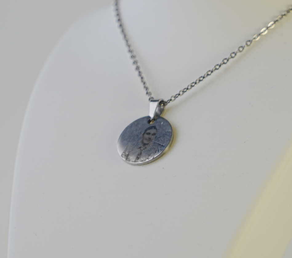 Silver necklace with a round pendant on a light gray background