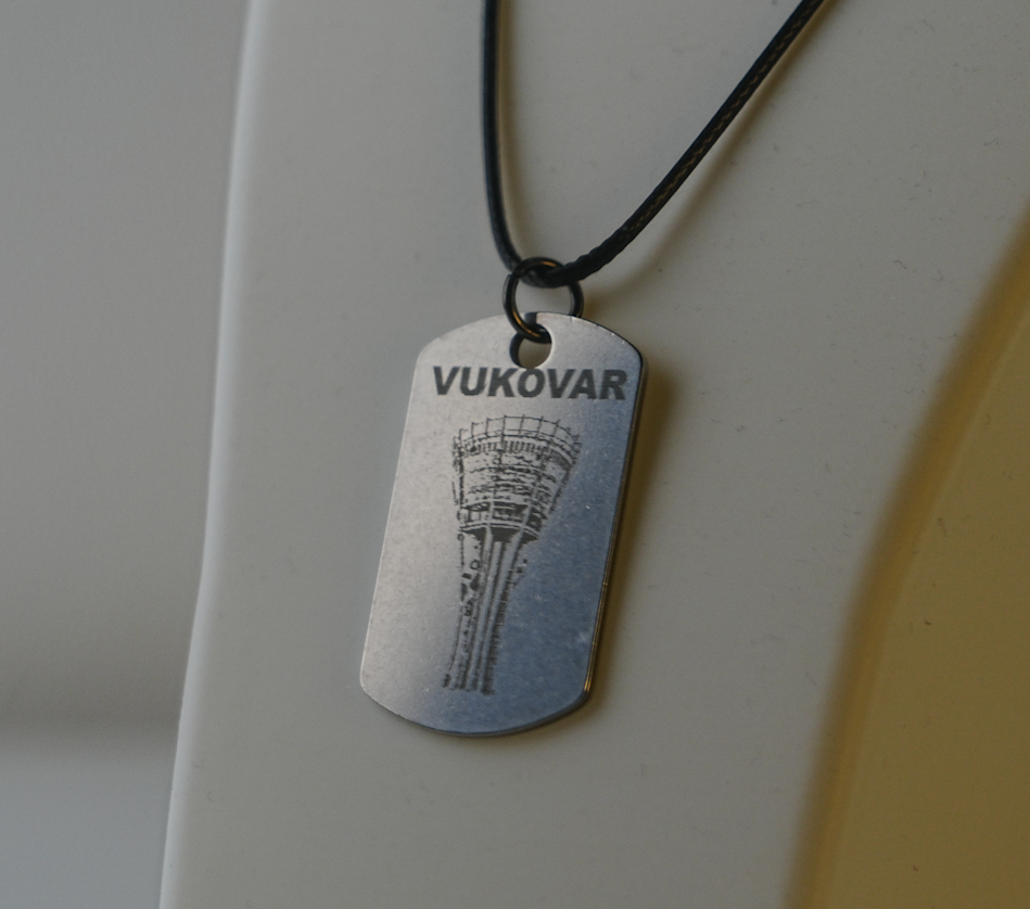 Silver dog tag with 'Vukovar' engraving on a black cord against a neutral background