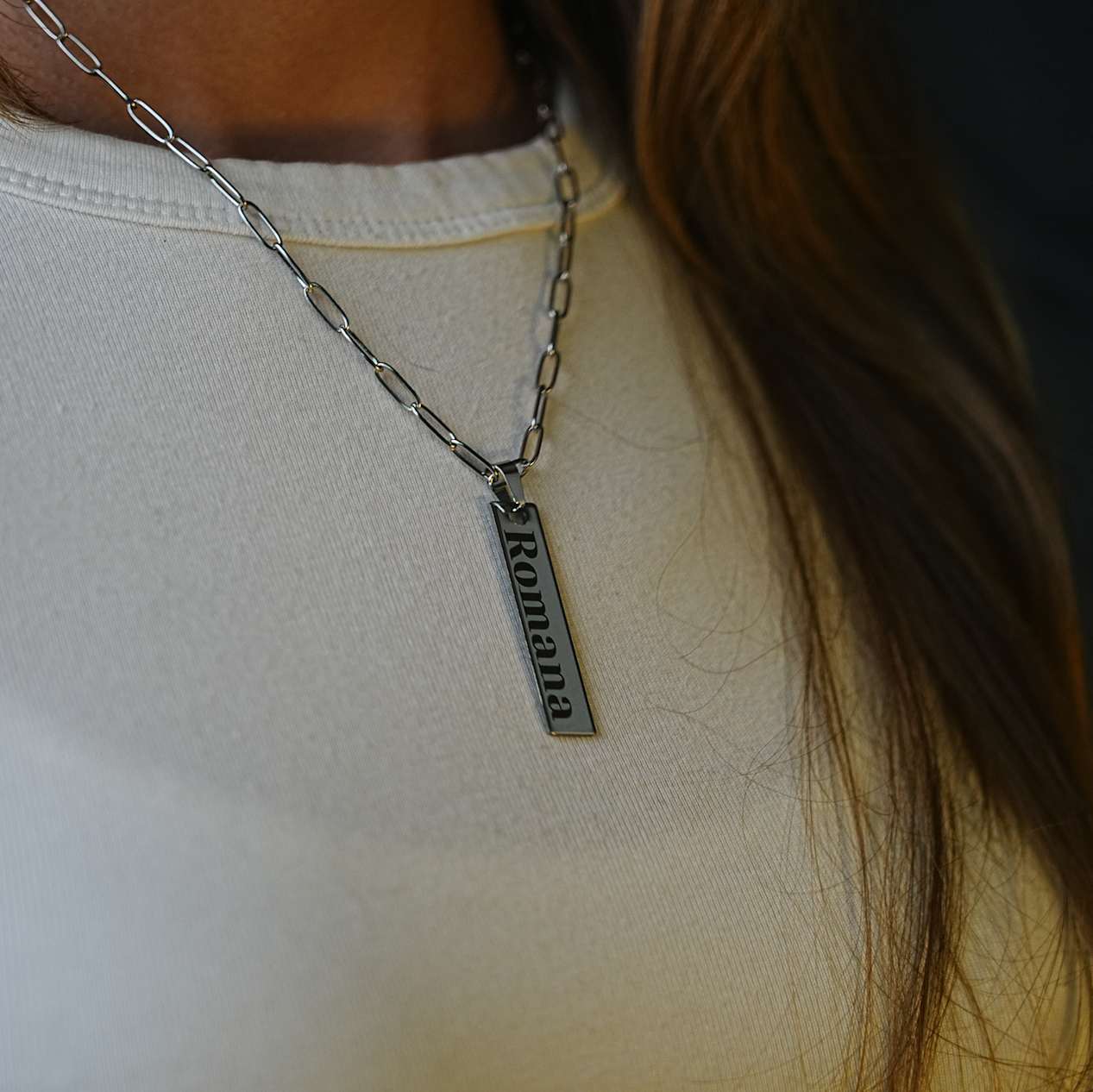 Silver necklace with a pendant on a person wearing a white shirt