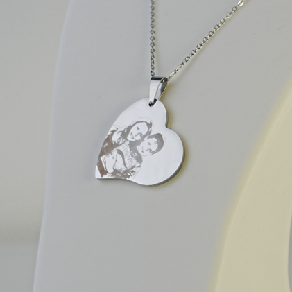 Heart-shaped silver pendant on a chain against a light gray background